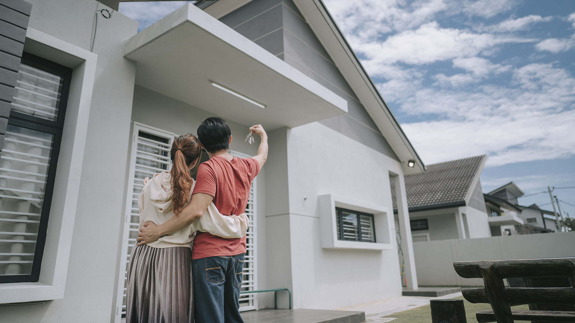 A couple posing outside their newly bought house, the home they are both financially committed to